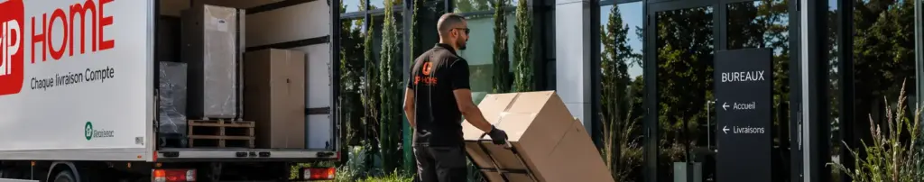 Livreur déchargeant un carton depuis un camion devant des bureaux