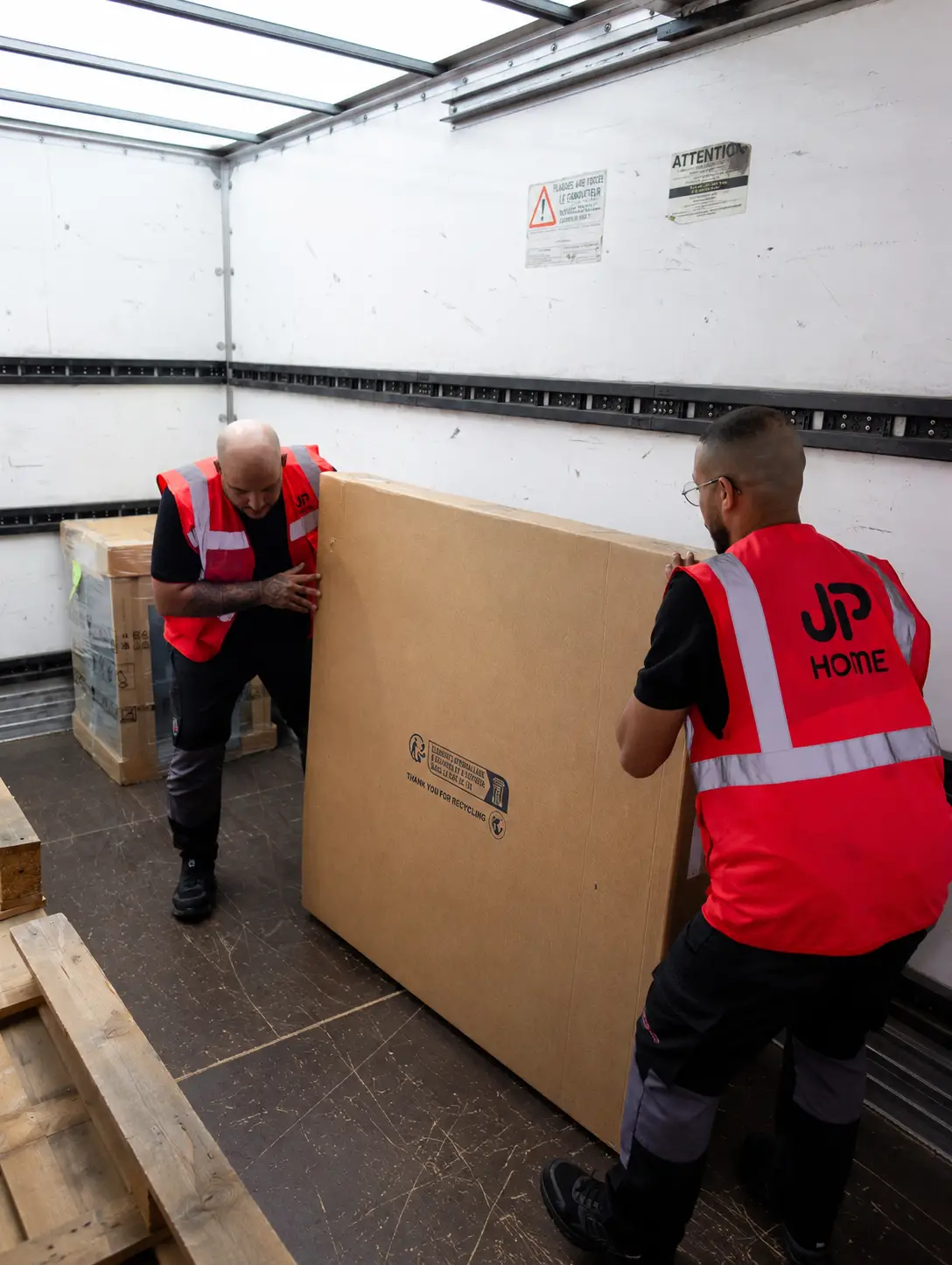 Deux livreurs JP Home portent un gros colis