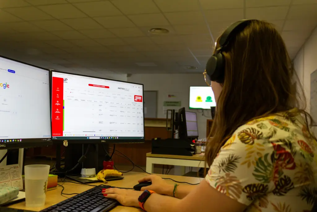 Femme portant un casque audio devant plusieurs écrans d’ordinateur au bureau