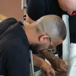 Dois homens montam uma cadeira branca seguindo as instruções da IKEA