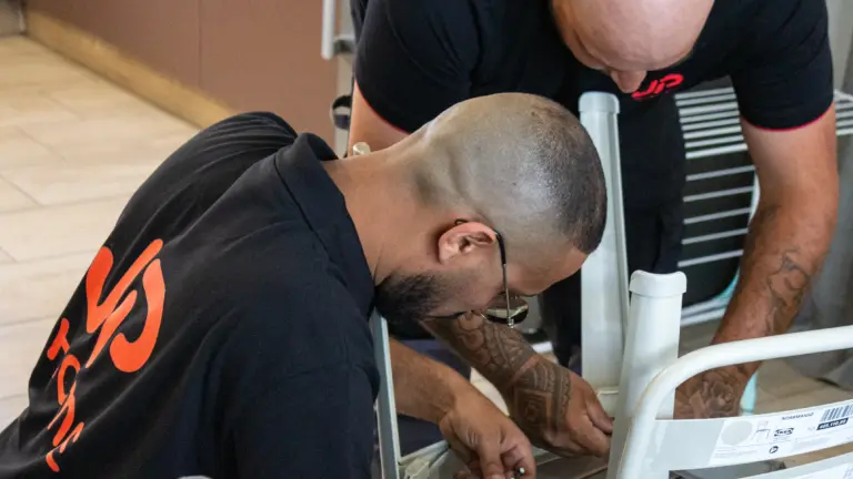 Deux hommes assemblent une chaise blanche en suivant la notice IKEA